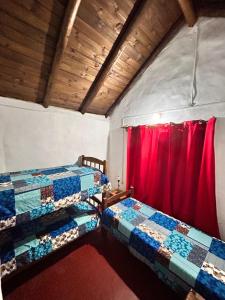 two beds in a room with a red curtain at El rancho - Espaciosa Casa para 7 en un Oasis de Tranquilidad in Villa Serrana