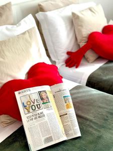 a newspaper and two red pillows on a bed at Gemelli-San Pietro-Trastevere-casa con posto auto in Rome
