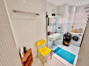 uma casa de banho com uma cadeira amarela e uma máquina de lavar roupa em FORUM 3 metro fast WiFi 400 Mbs TV HBO Disney+ em Varsóvia