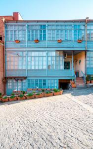 un edificio con ventanas azules y plantas delante de él en Old Tbilisi Located Near Botanical Garden, en Tiflis