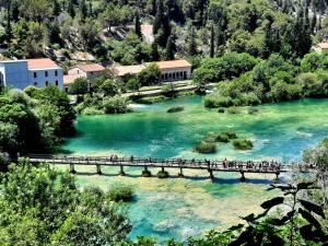 a group of people crossing a bridge over a river at Rural Villa Olive Krka- 30 min from sea, private pool, free parking, wifi, family friendly, park Krka 10 min in Ljubotić