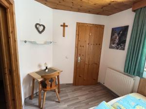 ein kleines Zimmer mit einem Holztisch und einem Kreuz an der Wand in der Unterkunft Apartment Familie Thomas und Angelika Melmer in Sankt Leonhard im Pitztal