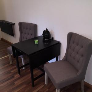 a black table with two chairs and a tea kettle on it at Elbsandstein Apartments Altstadt in Erfurt