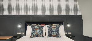 a bed with a black headboard and two pillows at The Coachman Hotel in Kilsyth