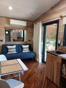 斯島的住宿－Polita Tiny House, con piscina, a 200m de la playa，一间带蓝色沙发的客厅和一间厨房