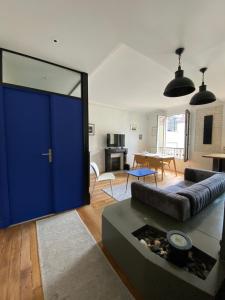 ein Wohnzimmer mit einem Sofa und einer blauen Tür in der Unterkunft Appartement à 50m de Paris in Clichy