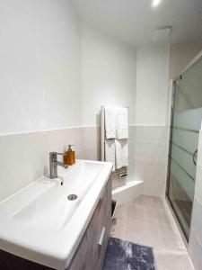 biała łazienka z umywalką i prysznicem w obiekcie La vie est belle à Paris Metro 9 w mieście Montreuil