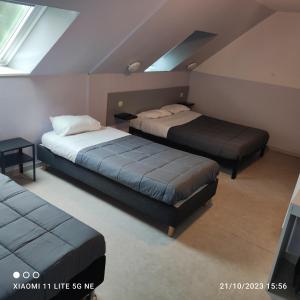 a bedroom with two beds and a tv in it at ENOR Hôtel in Guingamp