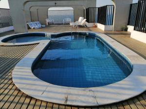a large swimming pool with blue tiles on a deck at Apartamento Praia de Iracema in Fortaleza