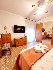 een slaapkamer met een bed en een tv aan de muur bij WHOLE FLAT CLOSE BEACH BREAKFAST KITCHEN AIR CONDITIONING LAUNDRY SHUTTLE AIRPORT WI-FI CAR PARKING NETFLIX BALCONIES CHECK IN 24H & METRO to ROME in Lido di Ostia