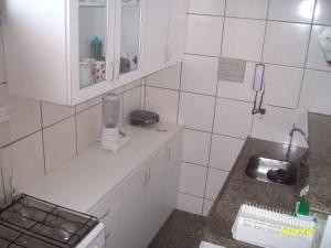 Elle comprend une petite cuisine avec un évier et du carrelage blanc. dans l'établissement Apartamento Praia de Iracema, à Fortaleza