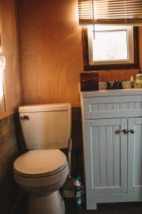bagno con servizi igienici, lavandino e finestra di Adirondack Country Living Tiny House Village a Canton