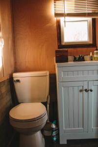 a bathroom with a toilet and a sink and a window at Adirondack Country Living Tiny House Village in Canton