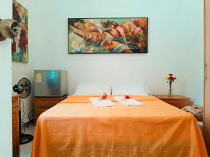 a bedroom with a bed with an orange sheet at Casa de huéspedes la Casona. in Medellín