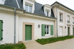a white house with a green door and green shutters at Maison proche Disney in Serris