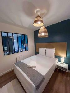 a bedroom with a large white bed with two windows at L‘Éden au Porte de Paris Metro 9 in Montreuil