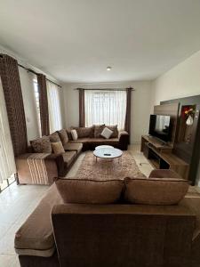 een woonkamer met een bank en een tv bij Arlshy furnished apartments in Kisumu