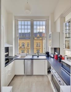 プラハにあるV Kolkovně 5 - Old Town Residenceの白いキャビネットと大きな窓付きの広いキッチンが備わります。