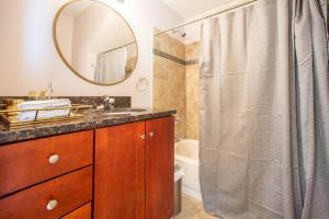 uma casa de banho com um lavatório e um chuveiro com um espelho. em Pilsen Paradise l 3 miles to DT em Chicago