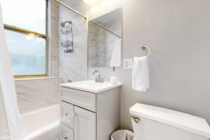 een witte badkamer met een wastafel en een toilet bij The Cozy Quarters - Sleeps 10 in Chicago