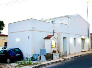 Un bâtiment blanc avec une voiture garée devant. dans l'établissement Una Vita In Vacanza, à Comiso
