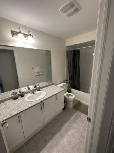 een badkamer met een wastafel, een toilet en een spiegel bij ON Residence in Hamilton