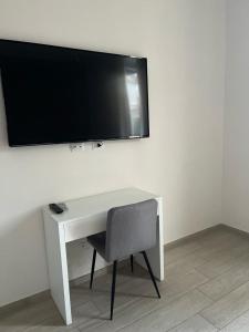 a white desk with a chair and a television on a wall at La Piazzetta Anzio in Anzio
