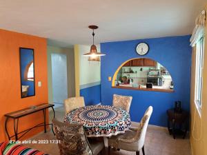una sala da pranzo con tavolo e orologio sul muro di Confortable y colorida casa con piscina a Cancún