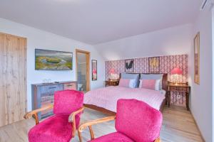a bedroom with a bed and two pink chairs at Residence Leo in Mariánské Lázně