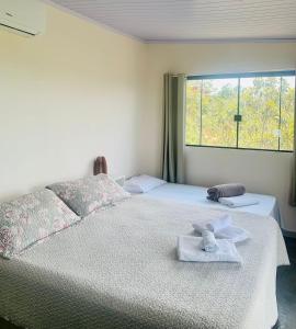 1 dormitorio con 2 camas, toallas y ventana en Chales Estrela Veadeiros, en Alto Paraíso de Goiás
