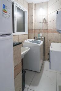 uma pequena casa de banho com um lavatório e uma máquina de lavar roupa em Maravilhosa vista para o mar e piscina - HB41F em Florianópolis