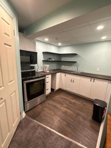 a kitchen with white cabinets and a stove top oven at Aiden Mansion in London