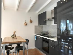 a kitchen with black cabinets and a wooden table at Superbe annAix de villa in Aix-en-Provence