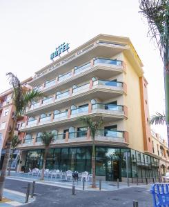 a large building with palm trees in front of it at Hotel Torremar - Mares in Torre del Mar