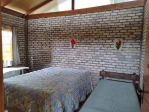 um quarto com uma cama e uma parede de tijolos em Sitio com jaccuzi, fogão a lenha em Vitória da Conquista