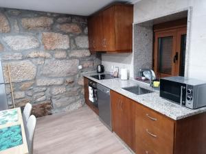 a kitchen with a stone wall and a microwave at Casa Soeira in Parada