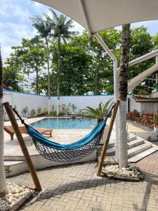 a hammock in front of a swimming pool at Bene Beach - Pousada Guarujá in Guarujá