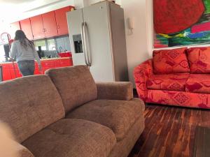 a woman in a kitchen with a couch and a red couch at Miraflores dpto 3 dormitorios in Lima