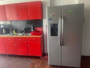 a kitchen with red cabinets and a refrigerator at Miraflores dpto 3 dormitorios in Lima