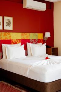 a bedroom with a large white bed with red walls at Golden Hill Parker Hotel in Elmina