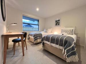1 dormitorio con 2 camas, escritorio y ventana en Luxury Villa, Central, Golf and Cafés - By KOSH BNB, en Hamilton