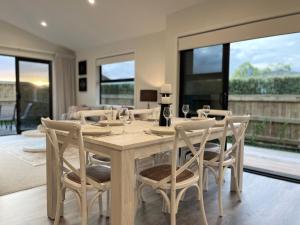 a dining room with a wooden table and chairs at Luxury Villa, Central, Golf and Cafés - By KOSH BNB in Hamilton