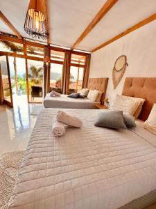 two beds in a room with large windows at Sababa Resort in San Pedro La Laguna