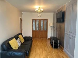 a living room with a black leather couch and a television at HAMS LODGE - - Strictly Only ONE GUEST ALLOWED IN ONE ROOM A SECOND ACCOMPANYING PERSON WILL NOT BE ALLOWED INTO THE PROPERTY in Birmingham