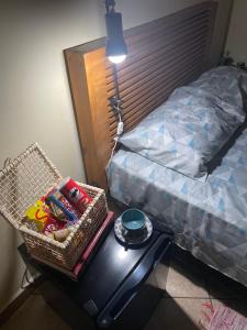 a table with a basket on it next to a bed at 1 quarto 1 cama queen size banheiro privativo- ap compartilhado in Alfenas