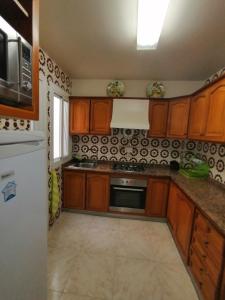 a kitchen with wooden cabinets and a white refrigerator at ROOMS Beach 5 MIN Playa in Alicante