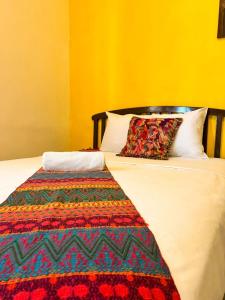 a bed with a colorful blanket and two pillows on it at Balamku Hotel Petit in Campeche