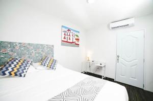 ein weißes Schlafzimmer mit einem weißen Bett und Kissen in der Unterkunft JM GUESTHOUSE in Santo Domingo