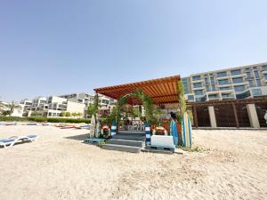 un cenador en una playa de arena con un edificio en Paradis De La Mer Al Zeina 507A1 en Abu Dabi