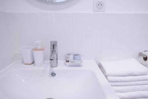 a white bathroom sink with a faucet and towels at Portes de Paris RER C à 2 min WiFi & Parking Inclus in Choisy-le-Roi